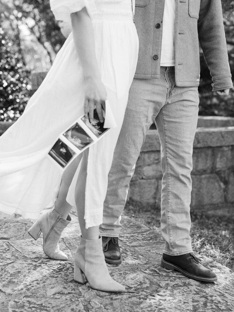 A close-up of a man and woman walking while the woman is holding a sonogram during a maternity photography in Virginia session by Katie Stansfield Photography.