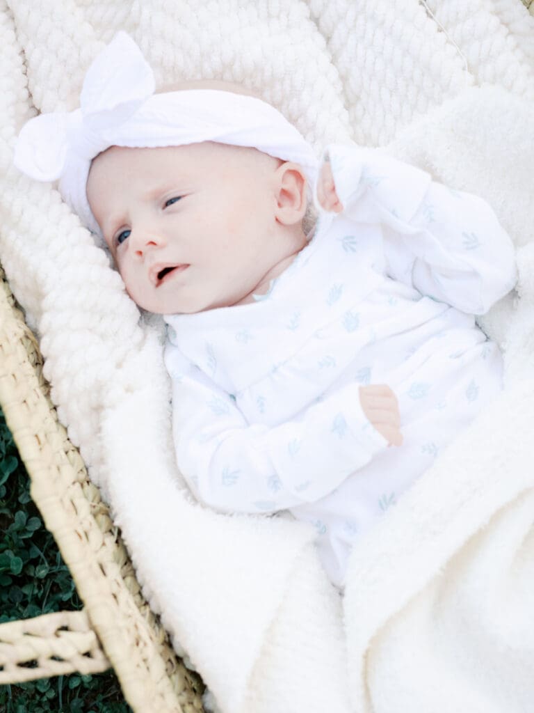 A newborn laying on top of blankets in a basket at an outdoor newborn photography in Virginia session by Katie Stansfield Photography.