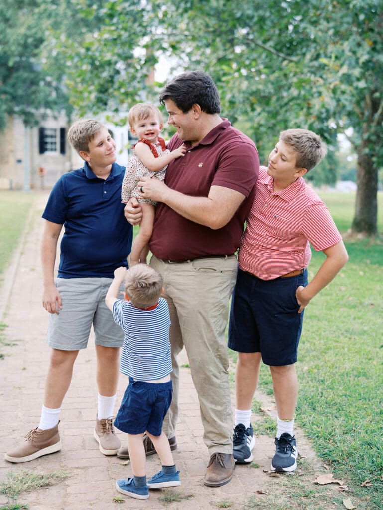 A dad holding and looking at his toddler while the other children look at the toddler at a Richmond fall mini session by Katie Stansfield Photography.