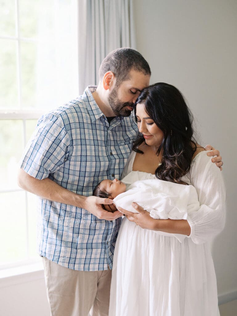 A mom holding and looking down at her baby as dad leans in to mom during a session by Katie Stansfield Photography, a Chesterfield newborn photographer.
