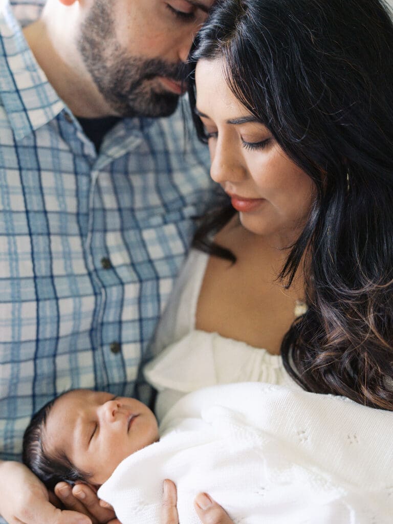 A mom looking down at her baby as dad leans in to mom during a session by Katie Stansfield Photography, a Chesterfield Newborn Photographer.