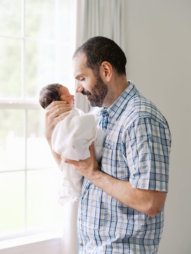 A dad holding and looking at his baby during a session by Katie Stansfield Photography, a Chesterfield Newborn Photographer.
