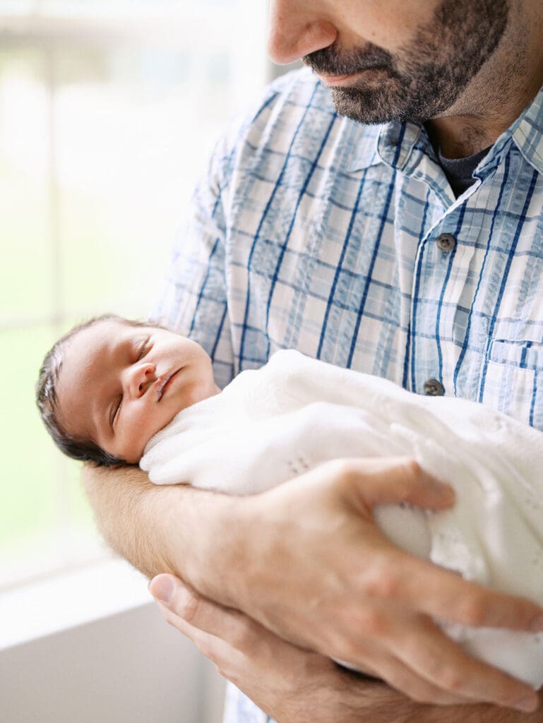 A baby held in dad's arms during a session by Katie Stansfield Photography, a Chesterfield newborn photographer.
