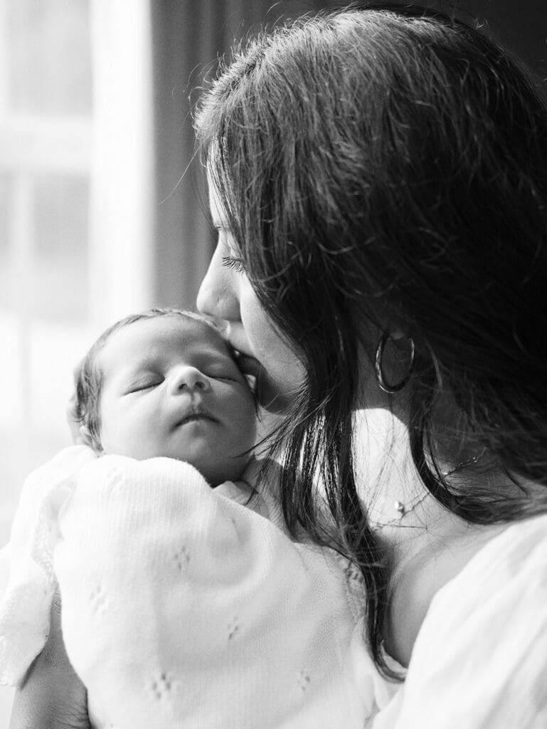 A mom kissing her baby during a session by Katie Stansfield Photography, a Chesterfield Newborn Photographer.
