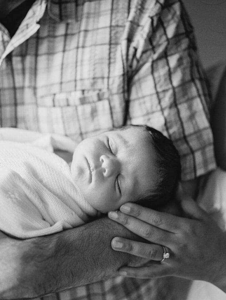 A baby sleeping while held in dad's arms during a session by Katie Stansfield Photography, a Chesterfield newborn photographer.