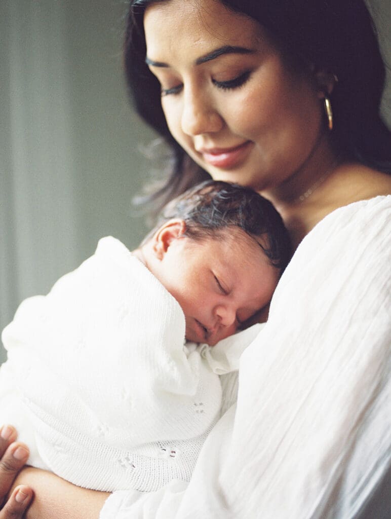 A mom kissing her baby as dad looks at them during a session by Katie Stansfield Photographer, a Chesterfield Newborn Photographer.