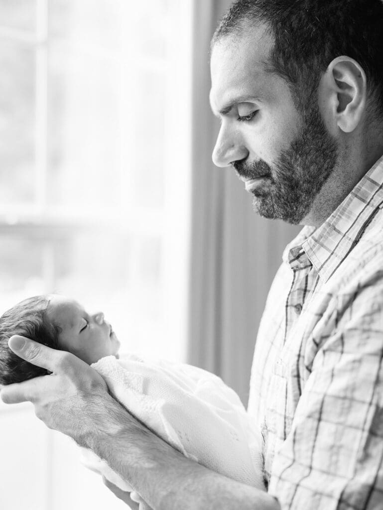 A dad holding and looking at his baby during a session by Katie Stansfield Photography, a Chesterfield Newborn Photographer.
