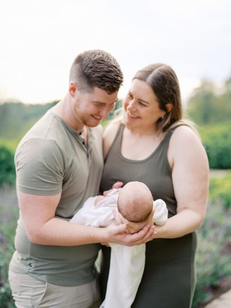 A mom smiling at dad as dad smiles at their baby during a newborn session by Katie Stansfield Photography.