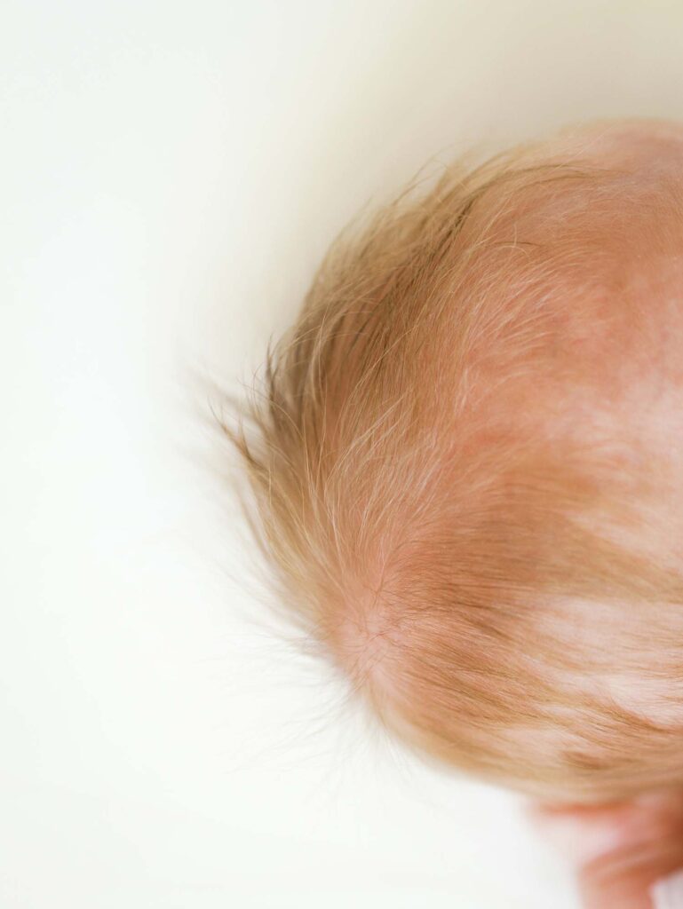 A close-up of a newborn's head of hair at the best time of day for newborn photos by Katie Stansfield Photography.