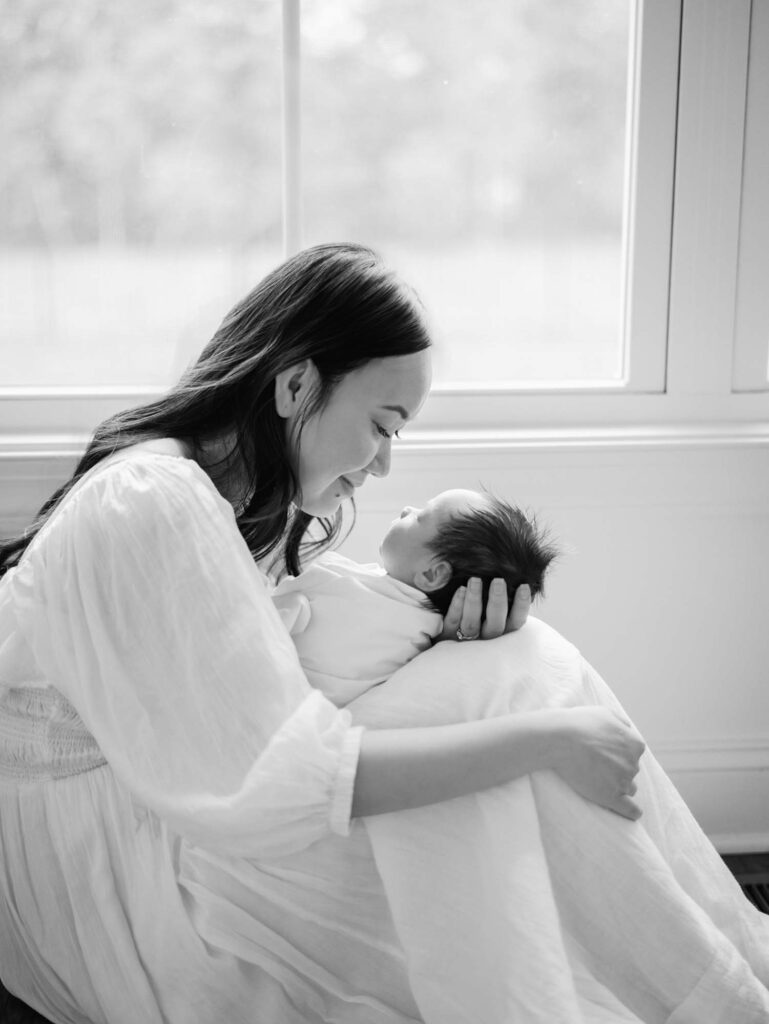 A mom looking at her baby at an in-home session by Katie Stansfield Photography.