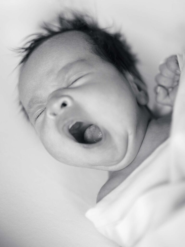A baby yawning at an in-home session by Katie Stansfield Photography, a Midlothian newborn photographer.