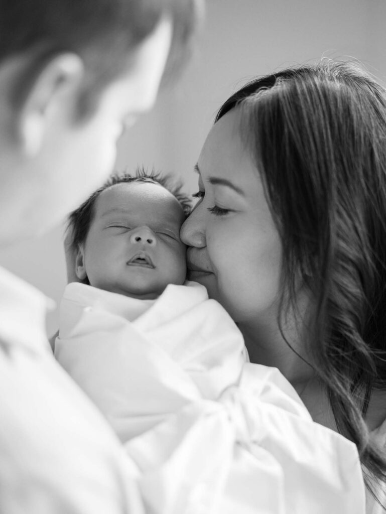 A mom kissing her baby at an in-home session by Katie Stansfield Photography, a Midlothian newborn photographer.