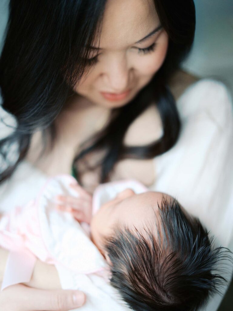 A mom looking down at her baby at an in-home session by Katie Stansfield Photography, a Midlothian newborn photographer.