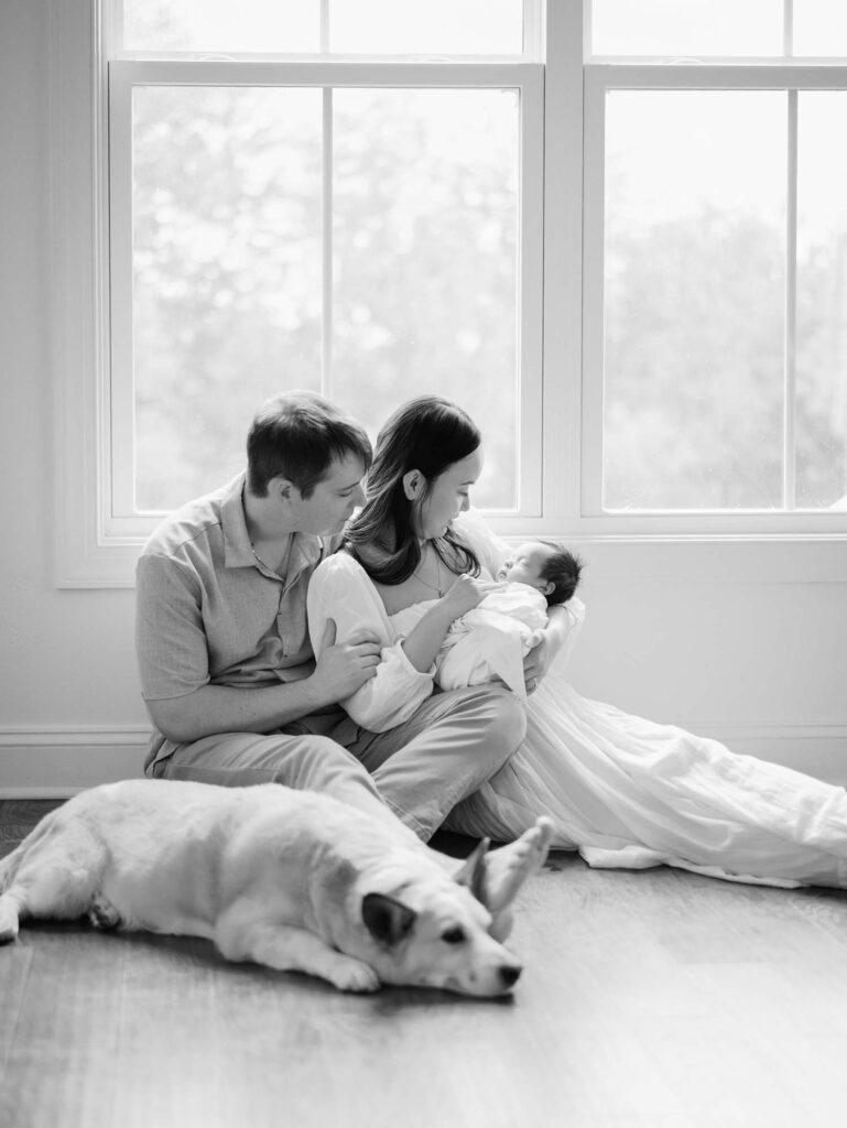 A mom and dad looking at their baby with their dog next to them by Katie Stansfield Photography.