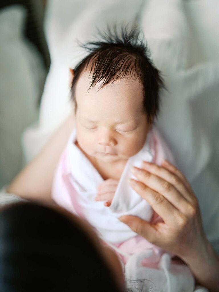 A baby sleeping in her mom's lap at an in-home session by Katie Stansfield Photography.