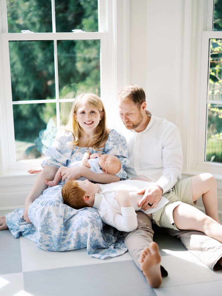 A family sitting and laying down as the mom smiles at a newborn session by Katie Stansfield Photography.