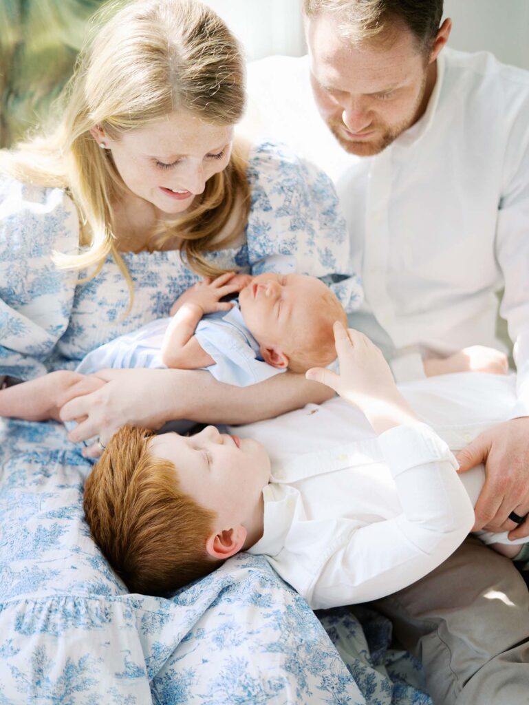 A young boy laying on his parents while playing with his baby brother by Katie Stansfield Photography, an Ashland VA newborn photographer.