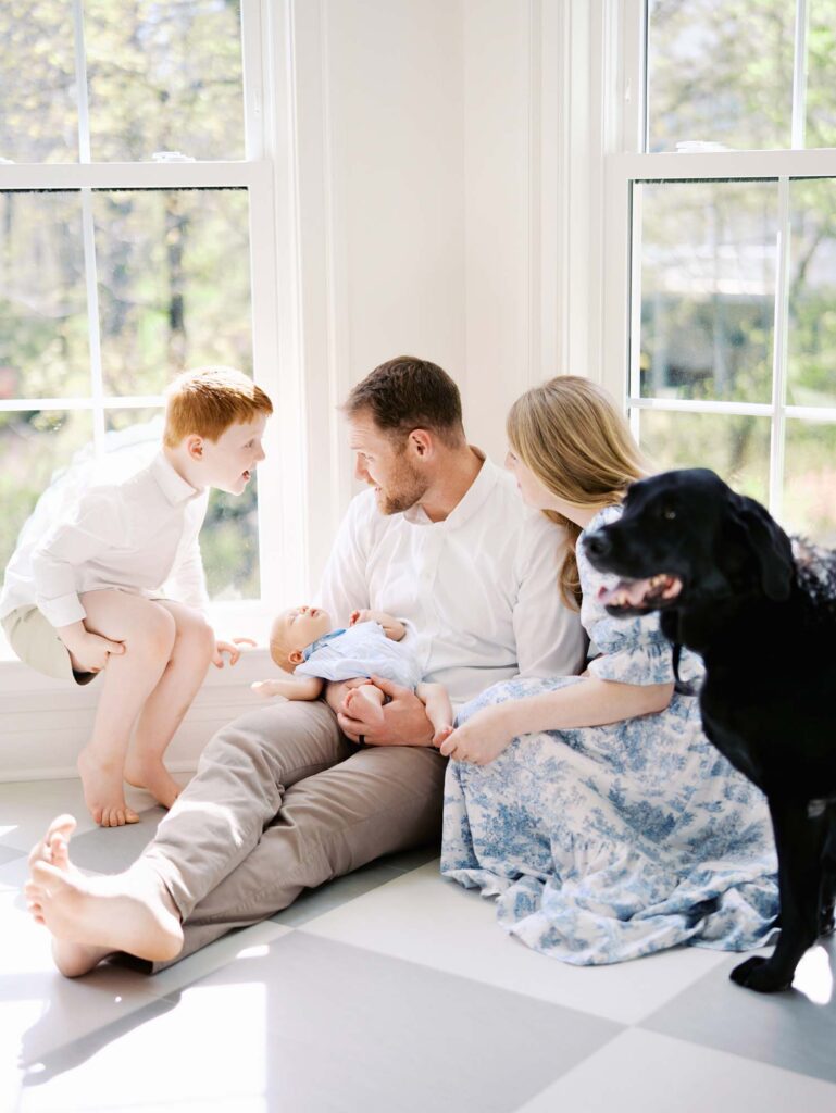 A family sitting with their baby as a young boy looks at his dad by Katie Stansfield Photography, an Ashland VA newborn photographer.
