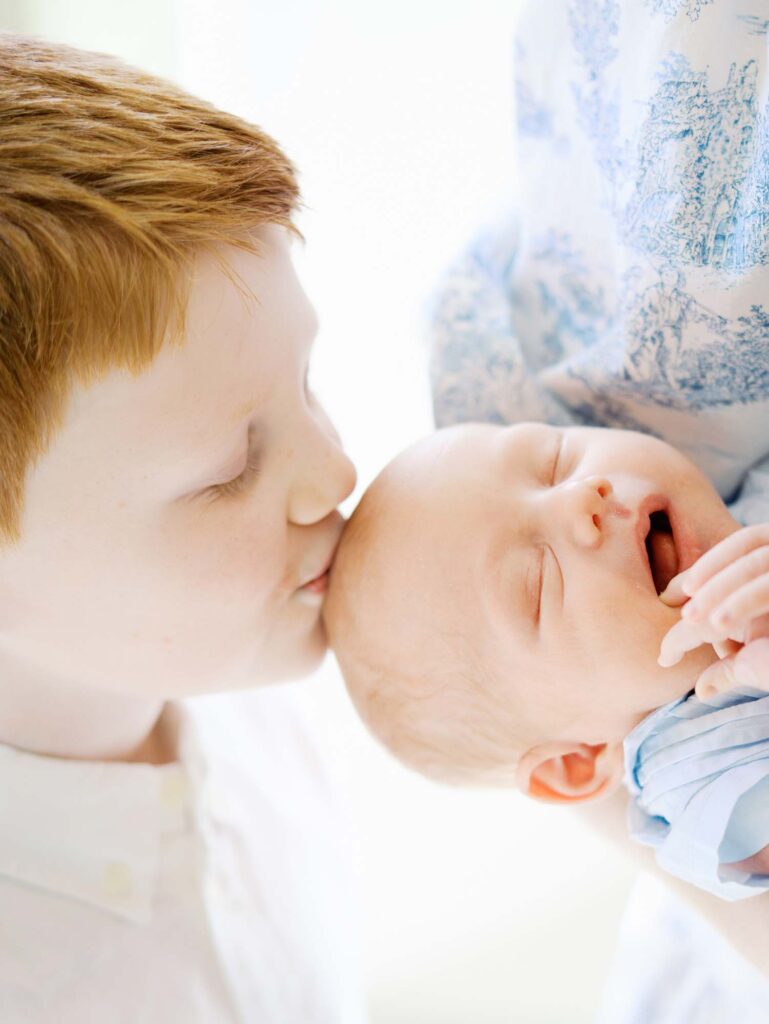 A young boy kissing his baby brother by Katie Stansfield Photography, an Ashland VA newborn photographer.