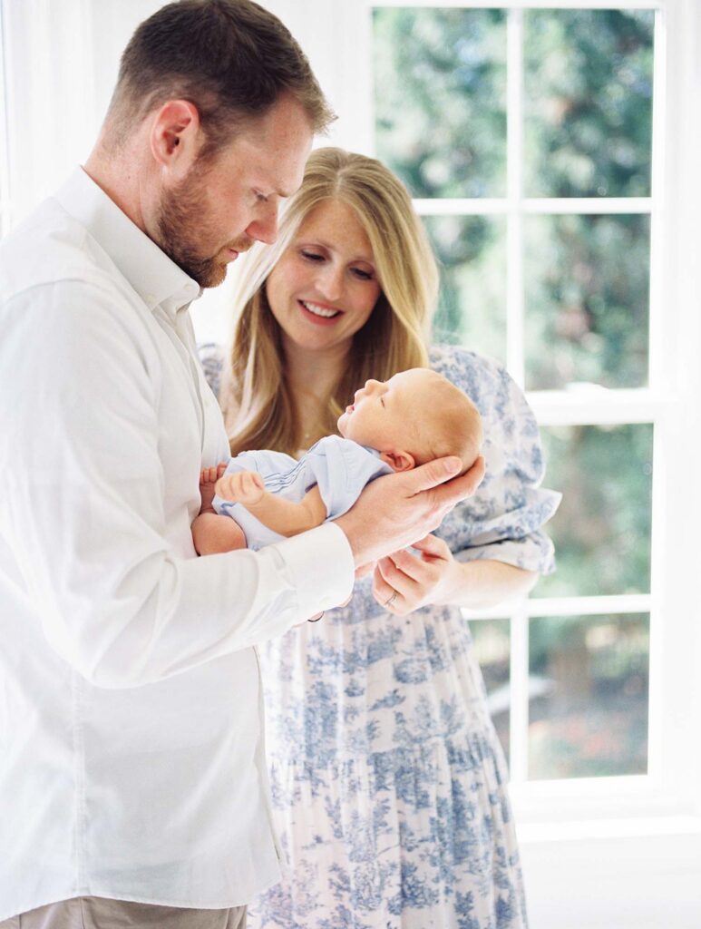 A mom and dad holding their baby at a newborn session by Katie Stansfield Photography.