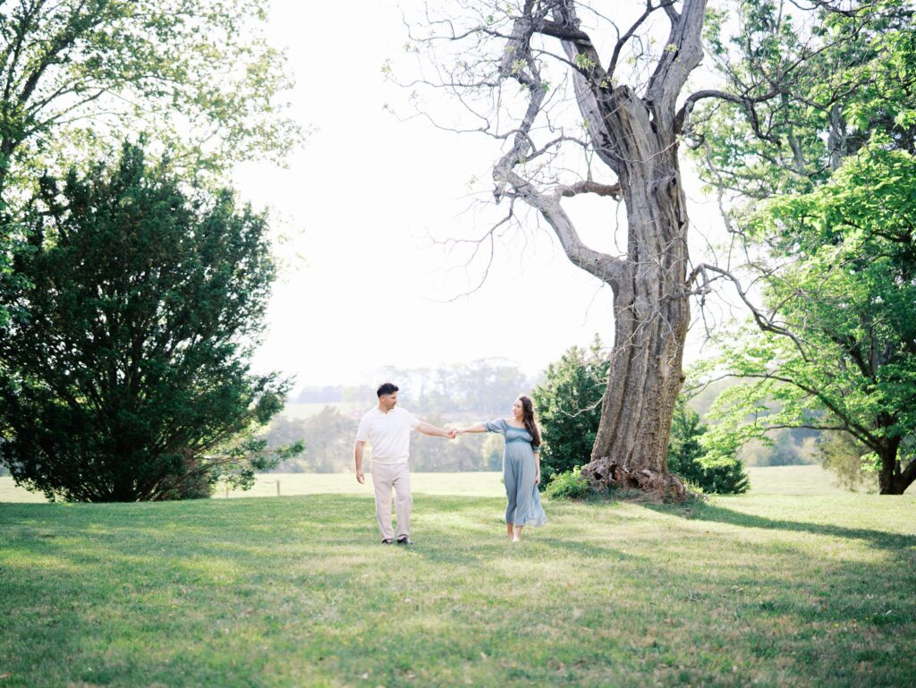 A couple holding hands and walking at a maternity photography session by Katie Stansfield Photography.