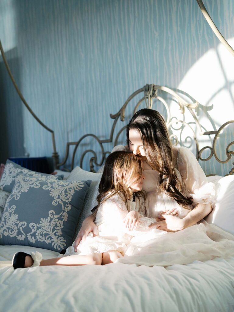 A mom and her daughter hugging on a bed at a maternity session by Katie Stansfield Photography, a Bon Air maternity photographer.