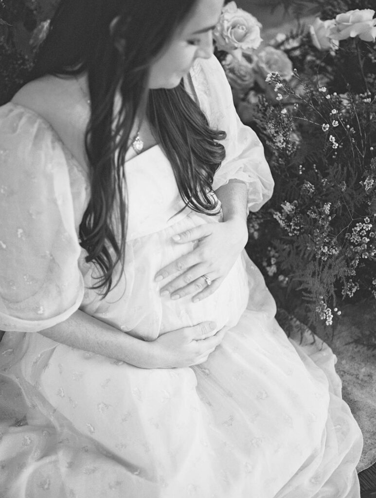 A close-up of a mom holding and looking down at her baby bump at a maternity session by Katie Stansfield Photography, a Bon Air maternity photographer.