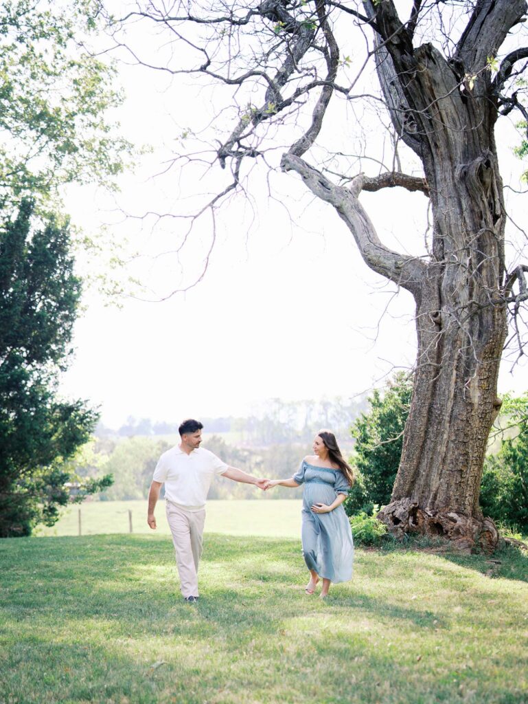 A couple holding hands and walking at a maternity photoshoot by Katie Stansfield Photography.