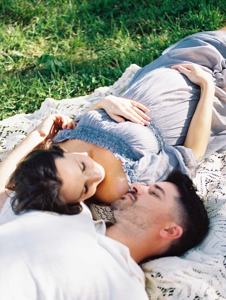 A couple laying down as mom holds her baby bump at one of the maternity photo locations in Henrico County, VA, by Katie Stansfield Photography.