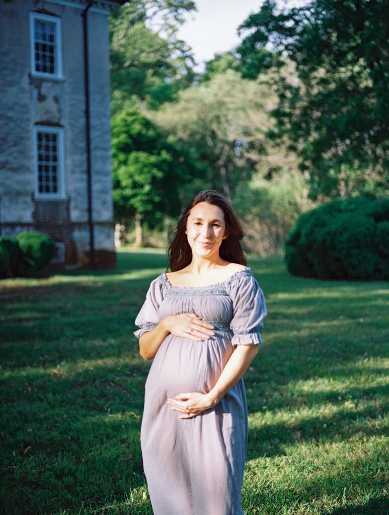 A mom smiling and holding her baby bump at a maternity session by Katie Stansfield Photography.