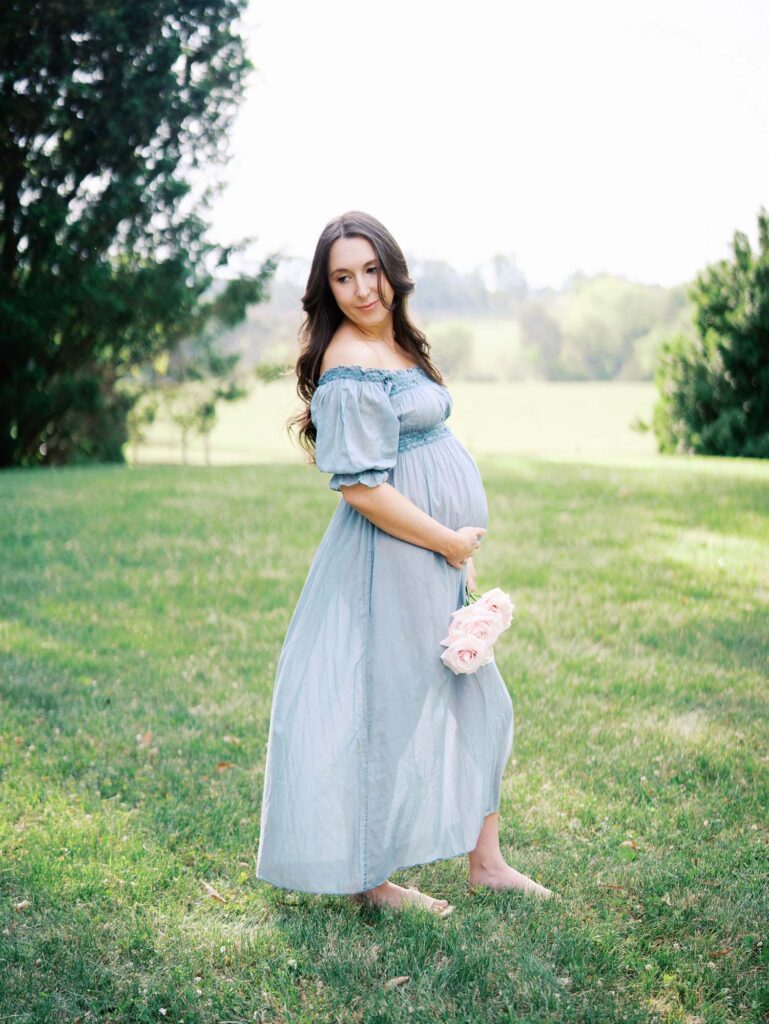 A mom looking down her shoulder and holding her baby bump by Katie Stansfield Photography.