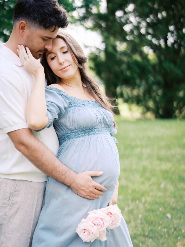 A couple posing and holding mom's baby bump getting maternity photos in Henrico County, VA by Katie Stansfield Photography.