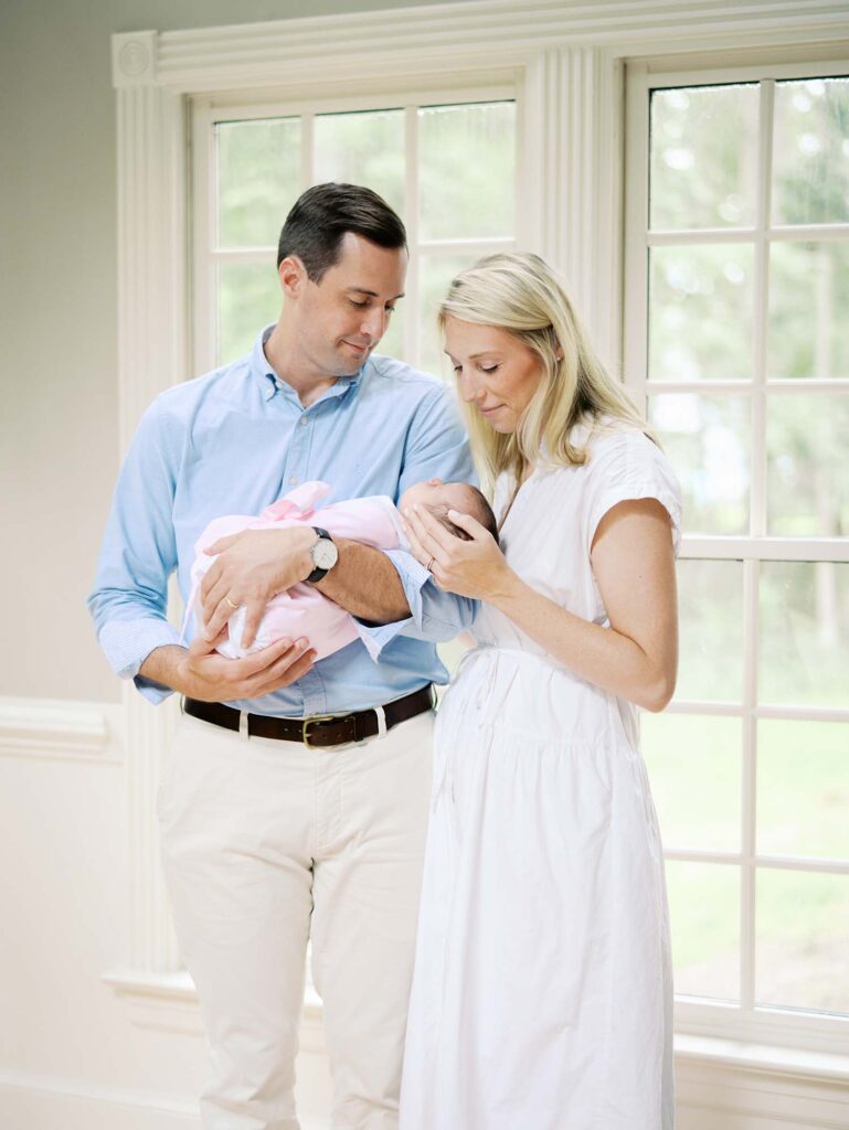 A mom and dad looking down at their newborn in their home, one of the newborn photo locations in Richmond VA, by Katie Stansfield Photography.