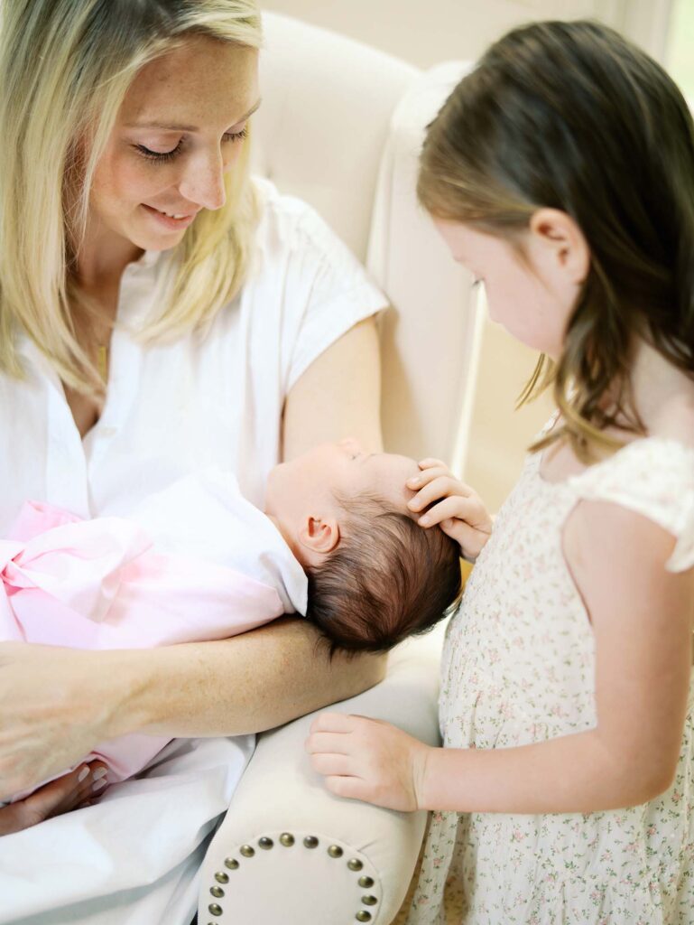 A mom holding her baby as sister touches baby's head in their home, one of the newborn photo locations in Richmond VA, by Katie Stansfield Photography.