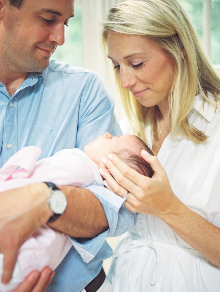 A mom and dad looking down at their newborn in their home, one of the newborn photo locations in Richmond VA, by Katie Stansfield Photography.