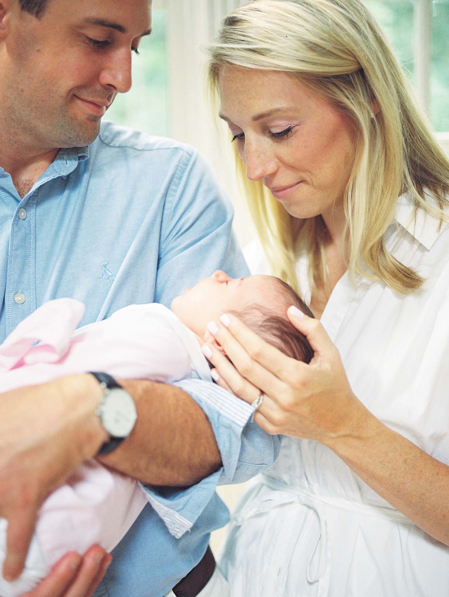 A mom and dad looking down at their newborn in their home, one of the newborn photo locations in Richmond VA, by Katie Stansfield Photography.