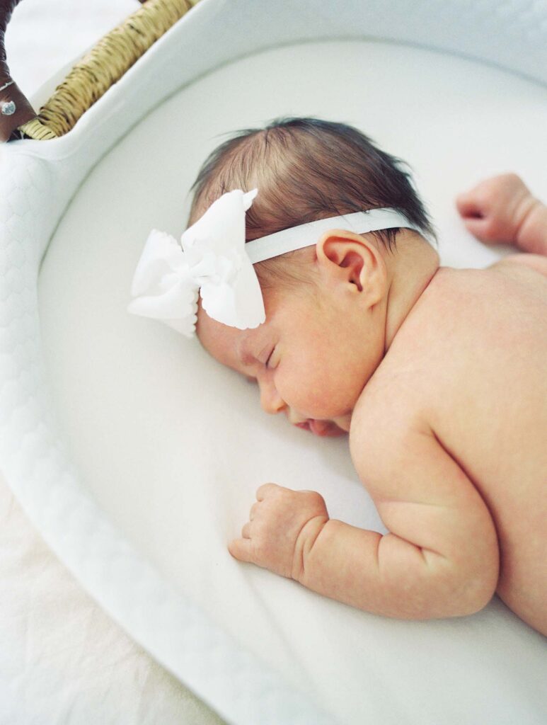 A baby sleeping in a basket at a newborn session by Katie Stansfield Photography.