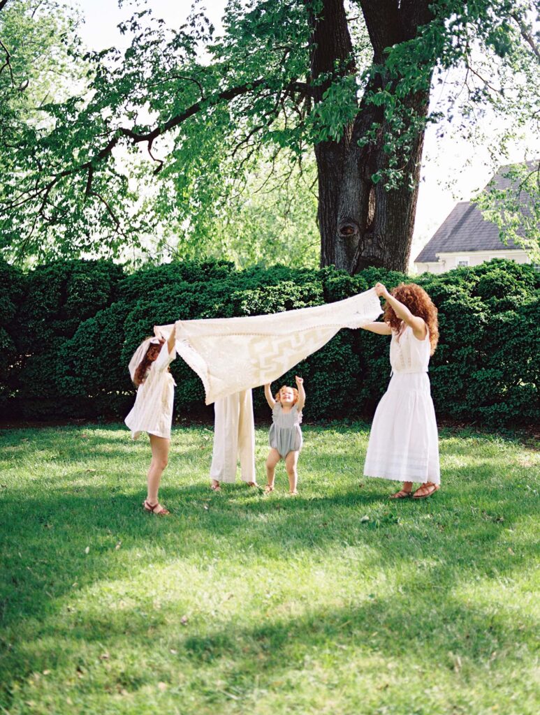 A family holding up a blanket at a family photo session by Katie Stansfield Photography.