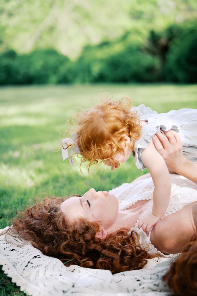 A mom holding up her toddler while laying on a blanket by Katie Stansfield Photography, a family photographer in Short Pump VA.