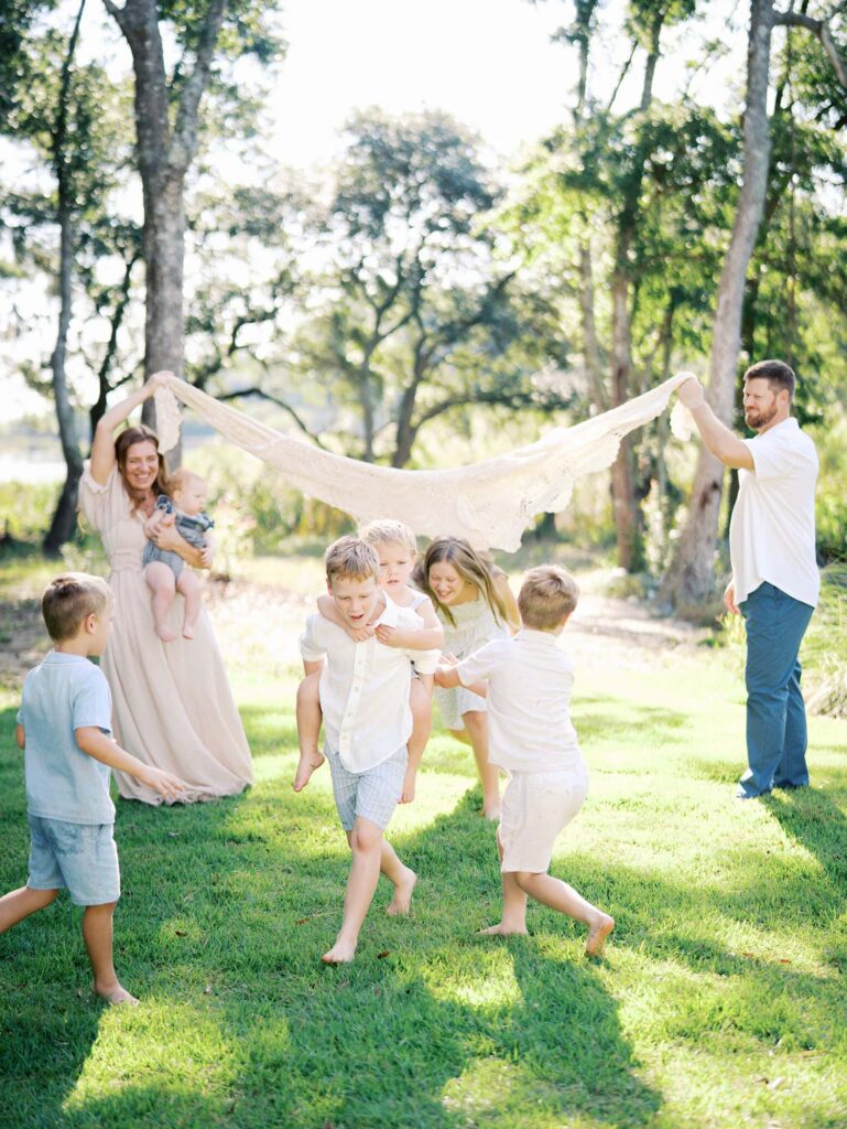 Mom and dad holding a blanket as kids run under it at an at-home family session by Katie Stansfield Photography, a Chesterfield family photographer.
