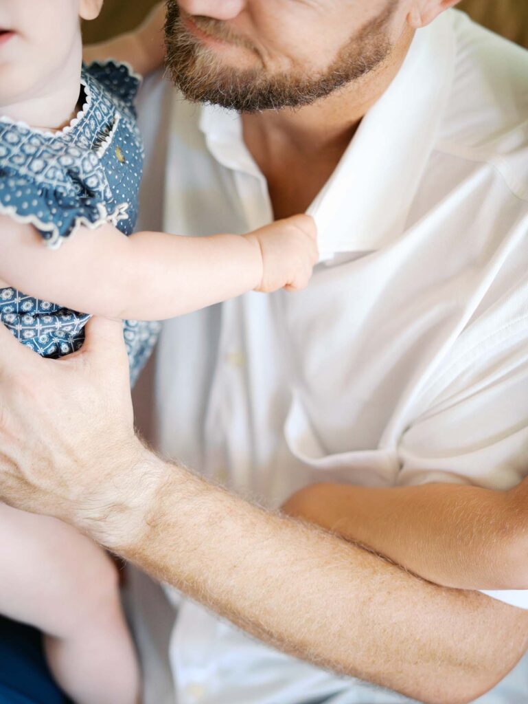 A close up of a baby holding onto dad's shirt at an at-home family photography session by Katie Stansfield Photography.