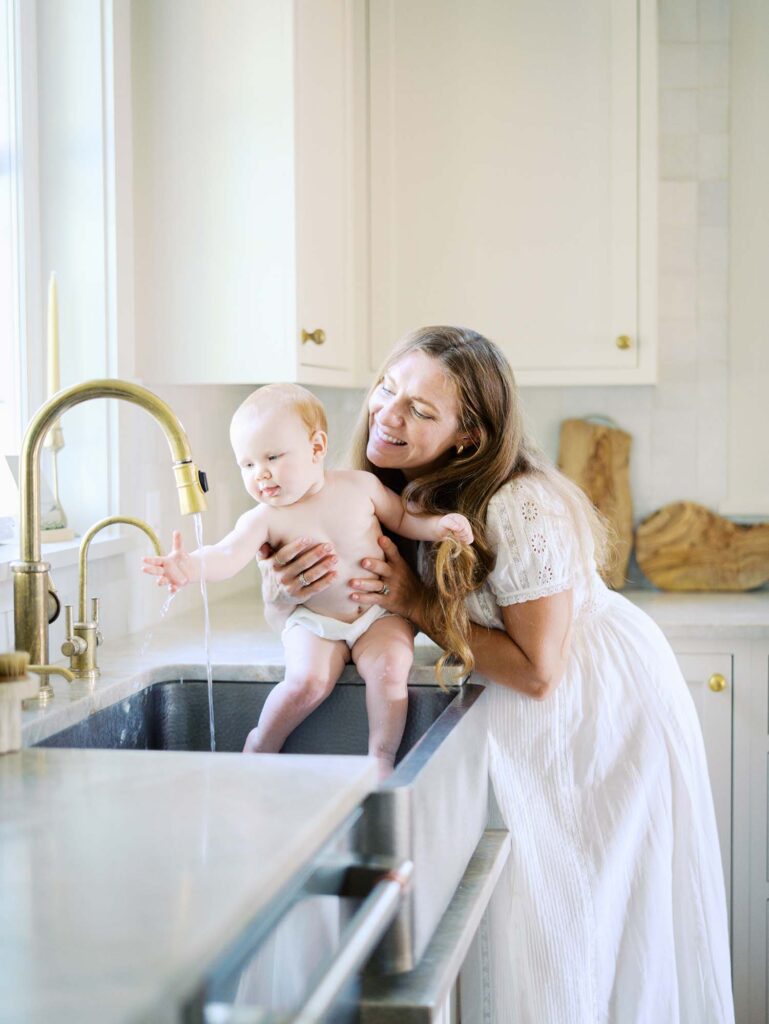 A mom giving a baby a sink bath at an at-home Chesterfield family photography session by Katie Stansfield Photography.