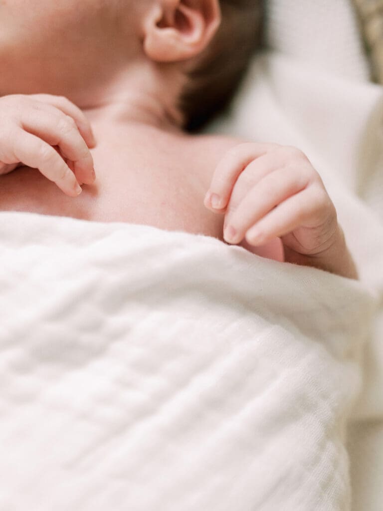 A close-up of a baby's hands while the baby is wrapped in a blanket at a Richmond in-home newborn photography session by Katie Stansfield Photography.