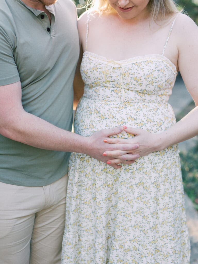 A close-up of a man and woman holding the woman's pregnancy bump during a maternity photography in Virginia session by Katie Stansfield Photography.