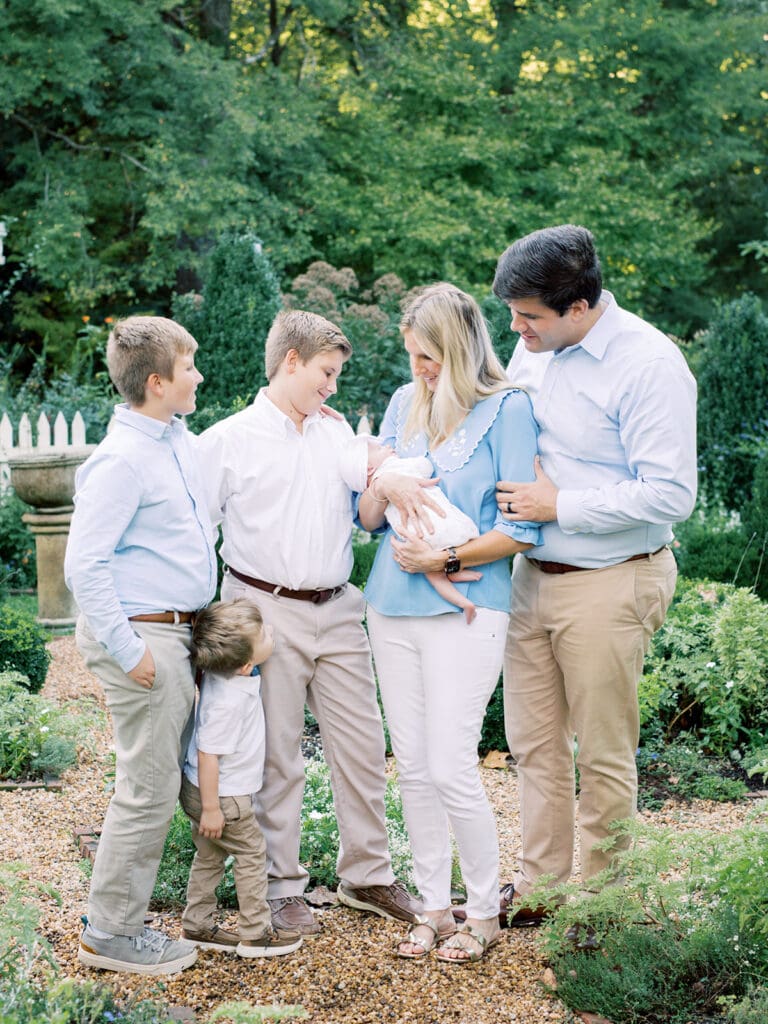 A mother holding her newborn while alongside family at an outdoor newborn photography in Virginia session by Katie Stansfield Photography.