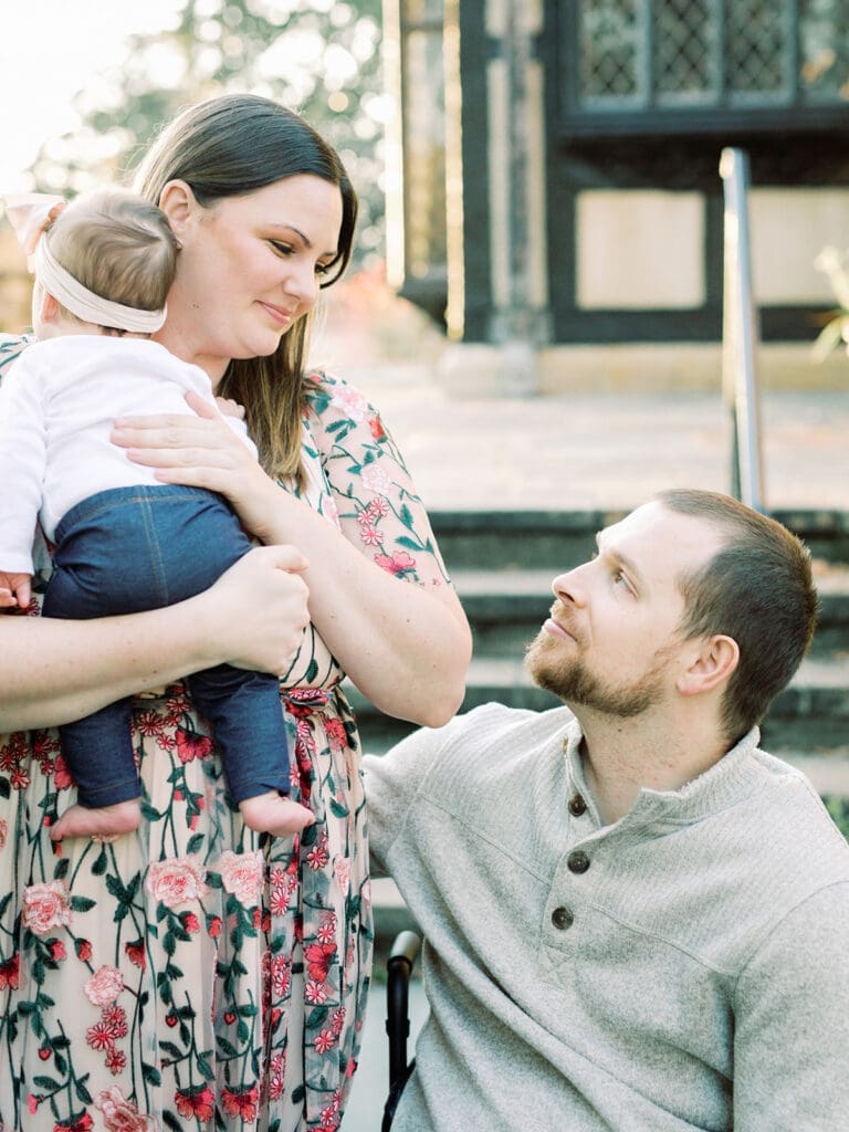 A man and woman looking at each other while the woman holds a baby at a Richmond family photography session by Katie Stansfield Photography.