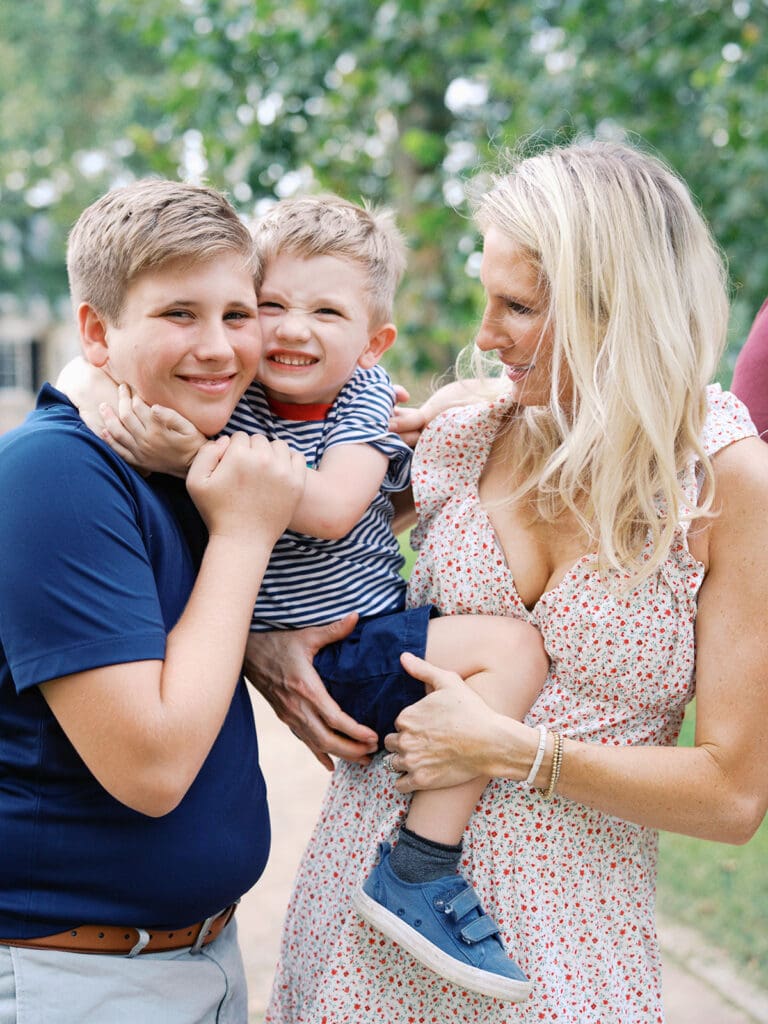 A mom holding and looking at her child as the child hugs his brother at a Richmond fall mini session by Katie Stansfield Photography.