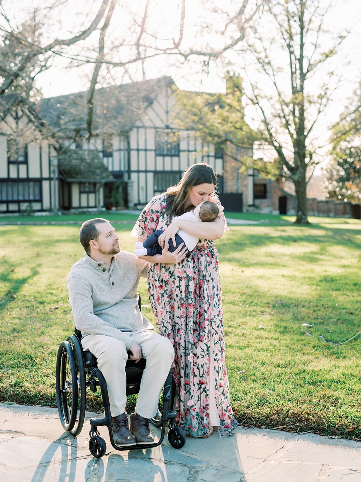 A mom kissing a baby with the dad next to them at a Richmond family photo session by Katie Stansfield Photography. Behind the family is a building with English architecture.