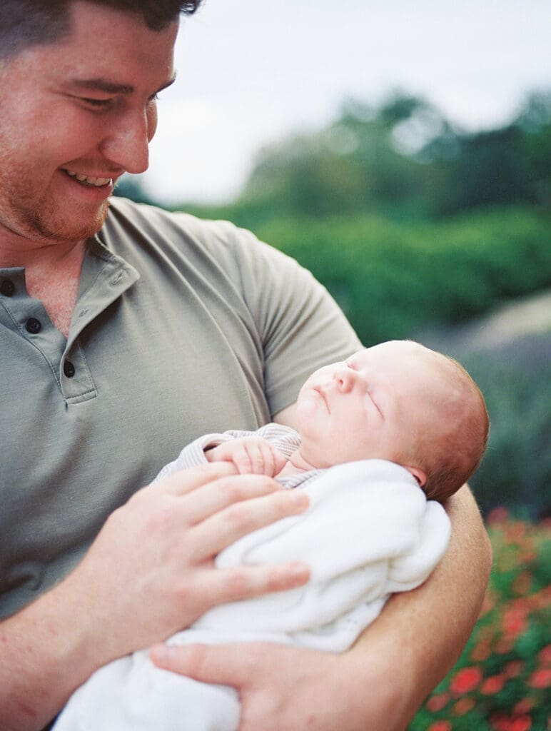 A dad looking at and holding his newborn during a Chesterfield newborn photography session by Katie Stansfield Photography.
