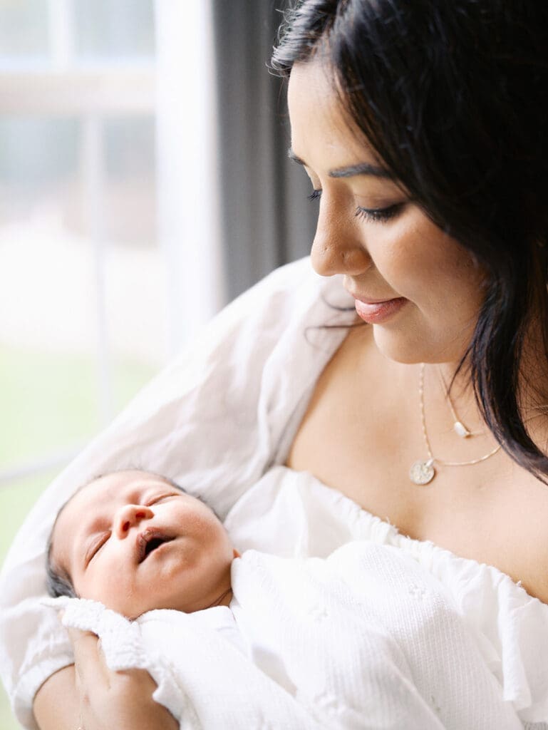 A close-up of mom holding a baby while looking down at the baby during a newborn photography session in Richmond, Virginia by Katie Stansfield Photography.